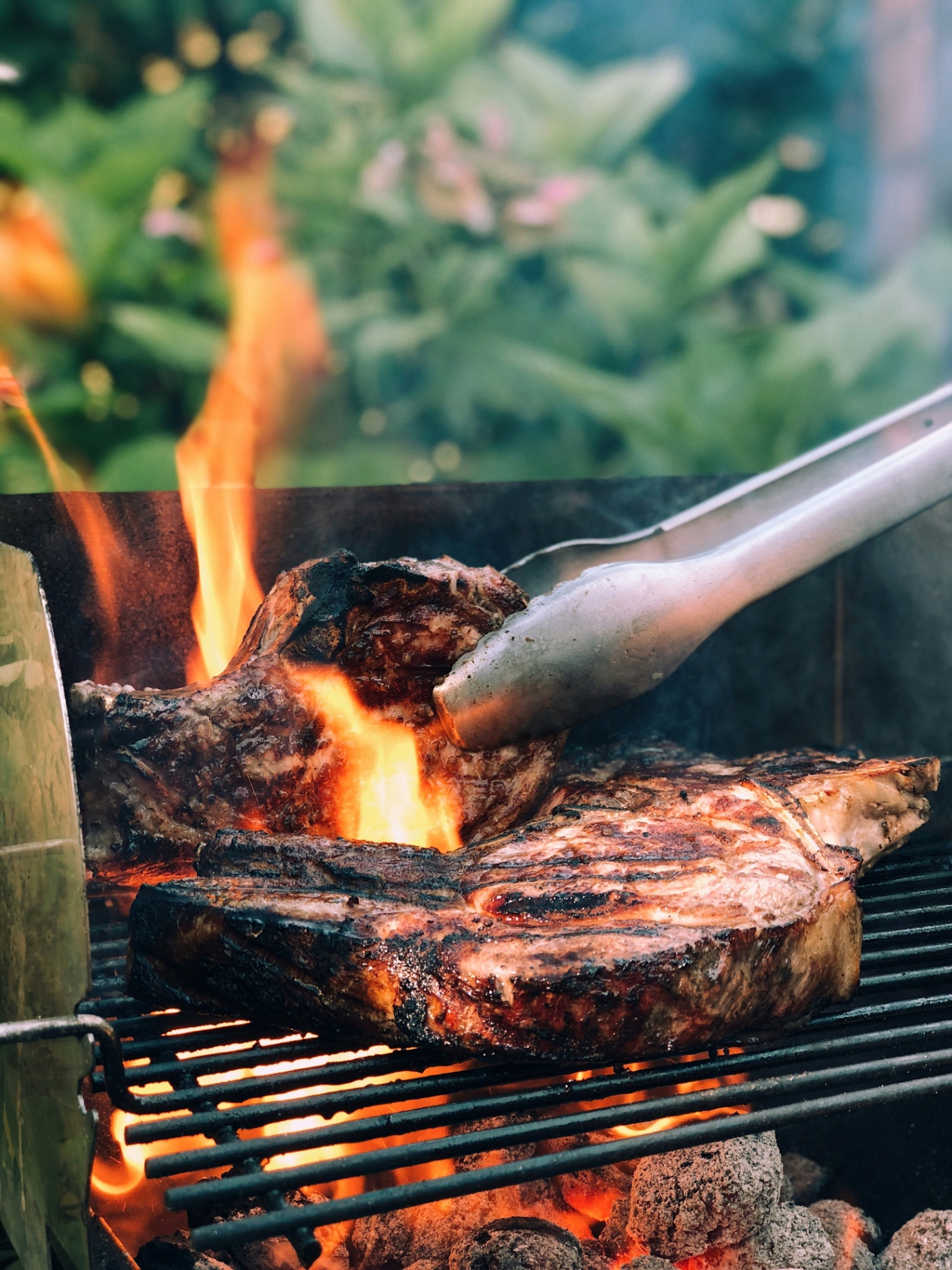 Tomahawk steak searing over open flame on a Cedar grill