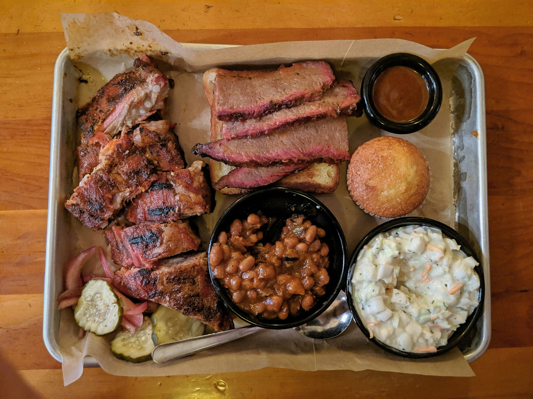 Cedar BBQ tasting tray with ribs, brisket, beans, and slaw